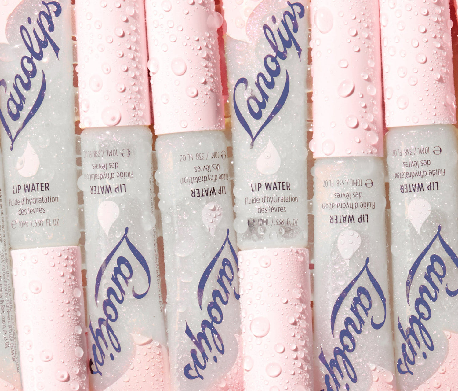 Multiple tubes of Lanolips Original Liquid Lip Water arranged in a row, covered in dewy water droplets. The silver and pink packaging features the Lanolips blue logo branding, and a droplet icon. Made with liquid lanolin, hyaluronic acid, glycerin and peppermint, this non-sticky, hydrating lip serum delivers deep moisture with an underwater holographic glow. Like a drink of water for your lips, it nourishes, softens and adds a glass like sheen - perfect dry lips and lip lickers.