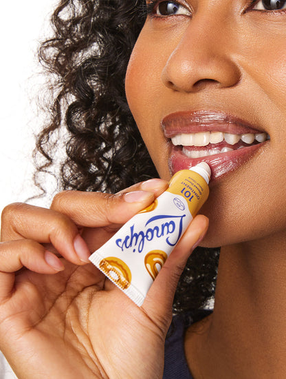 Model applying the Lanolips 101 Delicious in Glazed Donut lip balm.