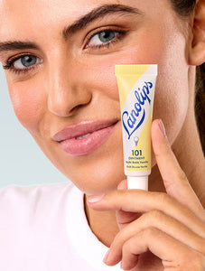 Model holding Lanolips 101 Ointment Multi Balm Vanilla. A super dense balm that seals in moisture and great for dry lips