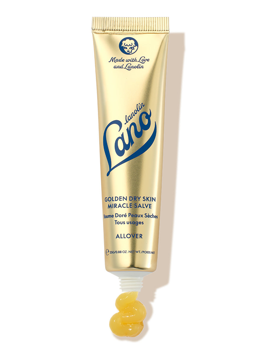 Lanolips Golden Dry Skin Miracle Salve 25g comes in a metallic gold squeezable tube with a white cap. The packaging features the Lano logo in deep blue lettering, along with ‘Made with Love and Lanolin’ inscribed at the top. A small amount of the rich, golden balm is shown oozing from the tube, emphasising its ultra-hydrating, multi-purpose formula designed to deeply nourish and repair very dry skin, hands, and rough patches.