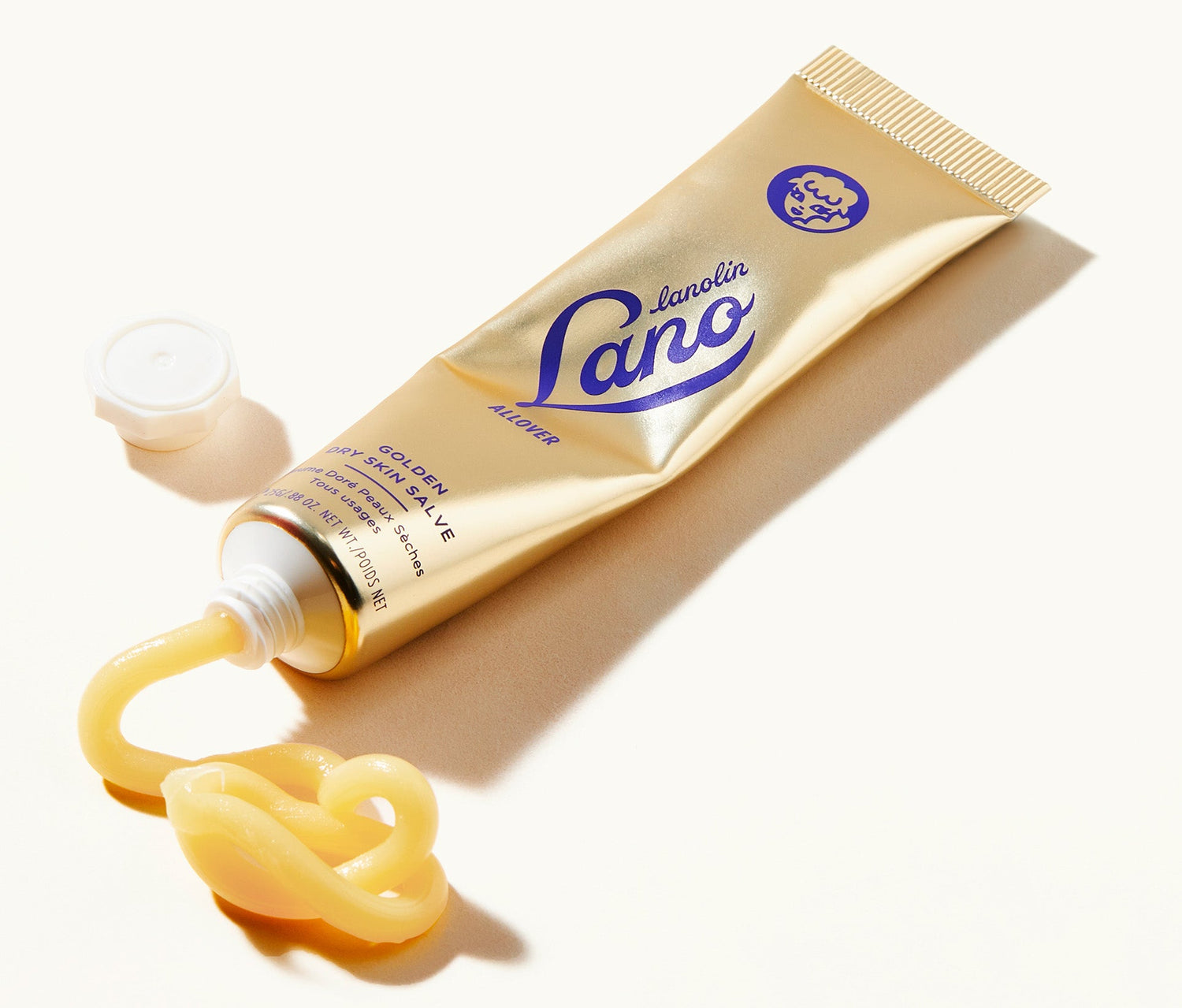 A tube of Lanolips Golden Dry Skin Salve lays on a white surface, with its rich, golden balm squeezed out. This 100% natural formula blends lanolin, antibacterial Manuka honey, and vitamin E to deliver intense hydration and protection. Designed for dry, rough skin, it provides up to 48 hours of deep moisture, soothing hands, feet, legs, face, and lips. Apply at night for soft, nourished, and revitalised skin by morning.