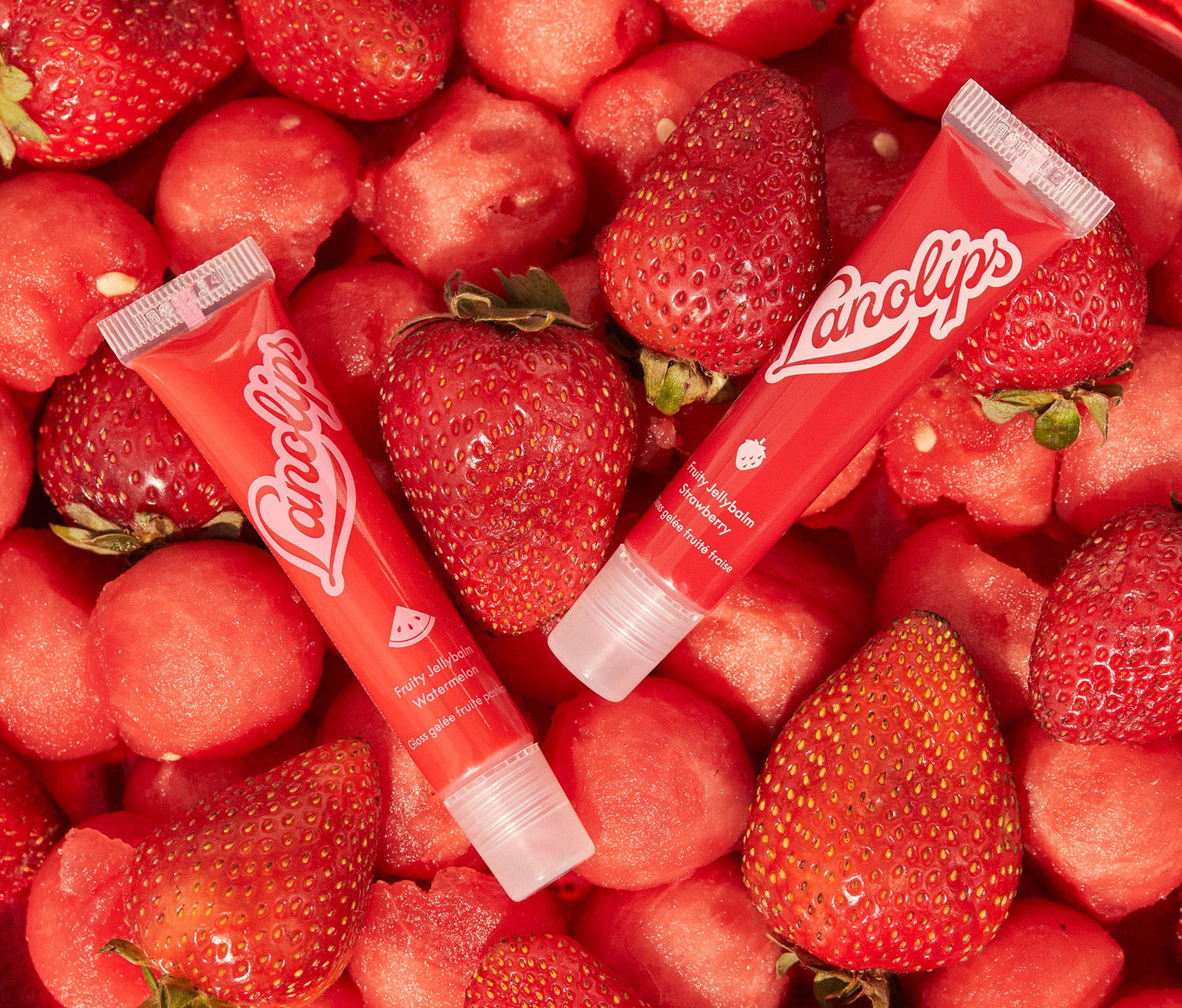 The Lanolips Jellybalm collection contains three fruity flavours: Strawberry, Watermelon and Cherry. The two tubes of Lanolips Jellybalms in Watermelon and Strawberry flavours, with vibrant red glossy packaging and pink lettering. The tubes are placed among fresh watermelon balls and strawberries. Made with ultra rich lanolin and all-natural fruit extracts, it's hydrating jelly for soft, glossy lips.