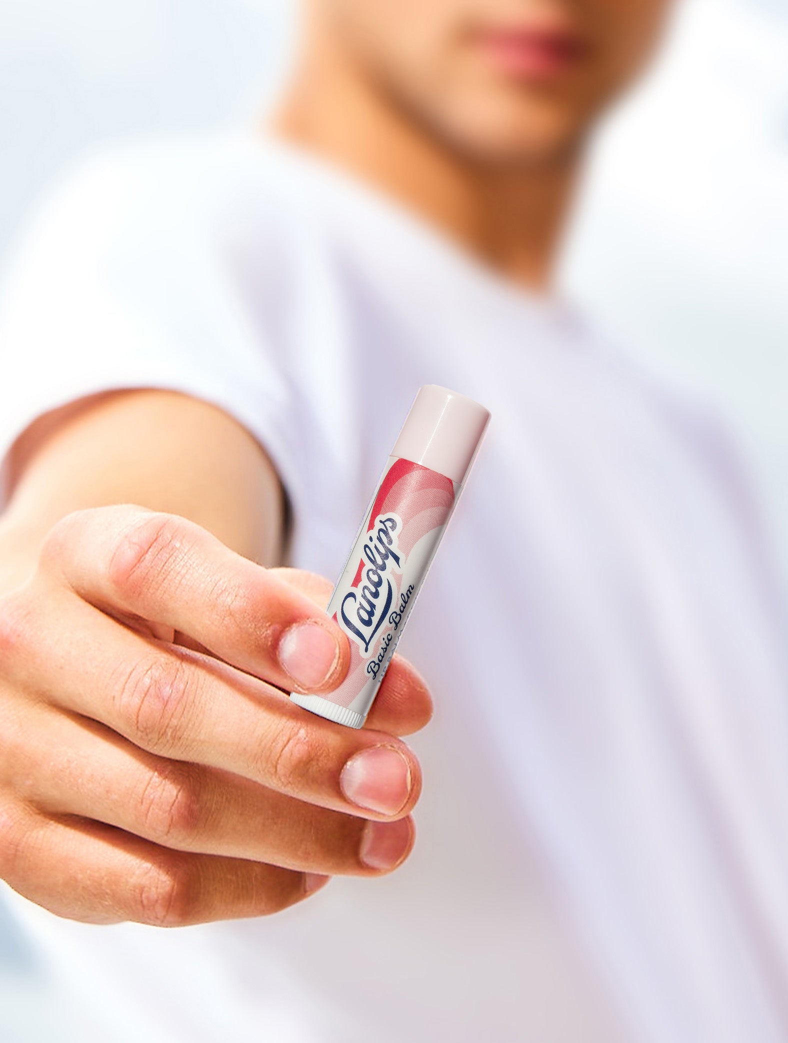 Lifestyle shot of a person holding a  Lanolips Basic Balm Strawberry.