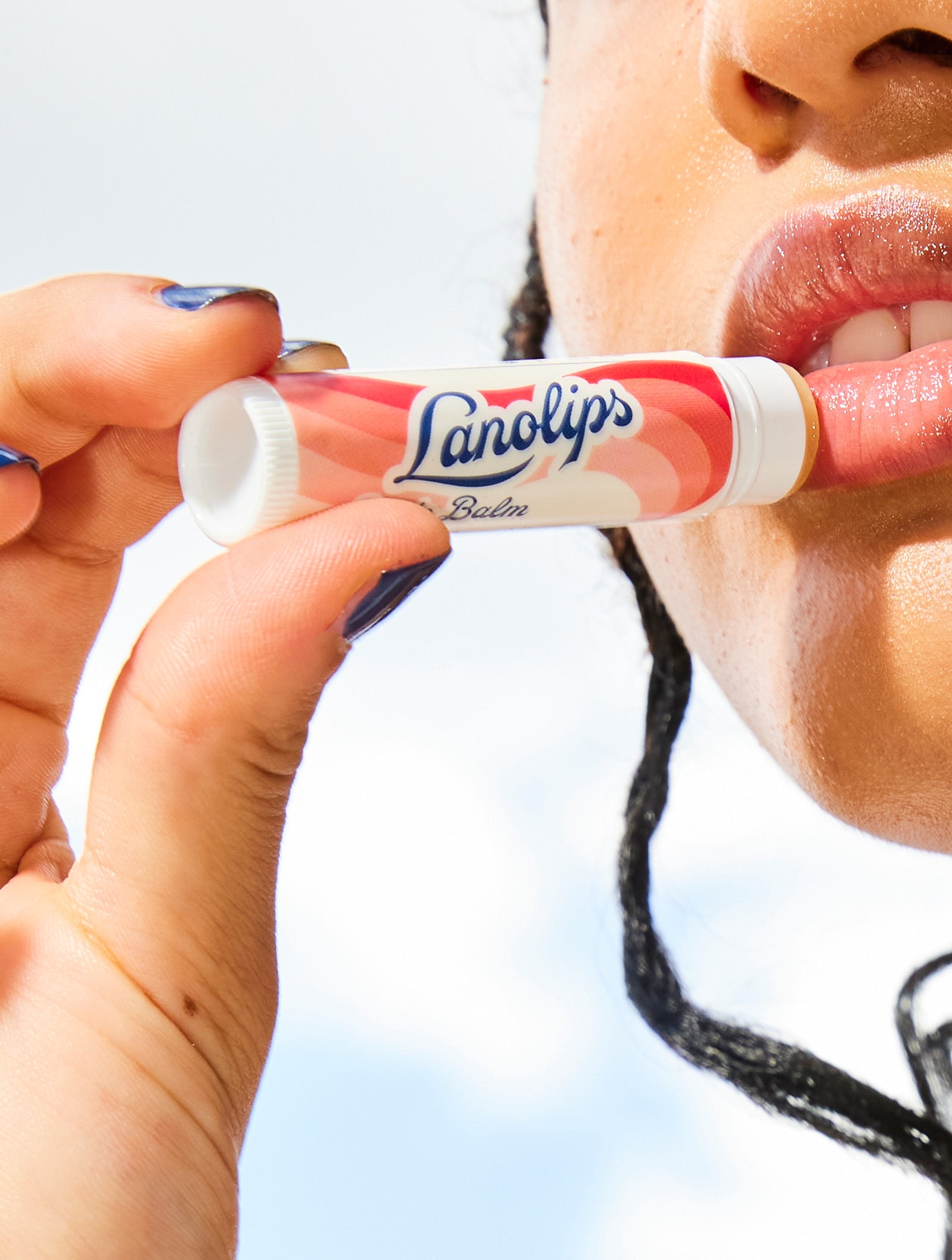 Model applying Lanolips Basic Balm Strawberry. 