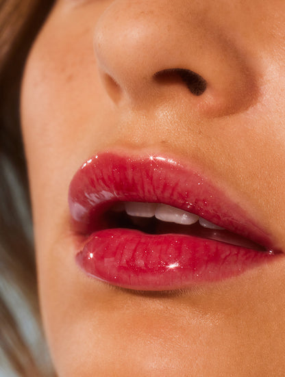 Close up image of a model lips wearing lanolips glossy balms berry lip balm.