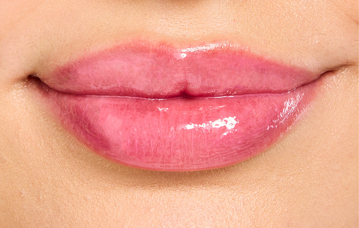 Close up of model's lips after applying Lanolips Hyaluronic Lip Oil in Raspberry. Infused with all-natural lanolin, vitamin e, and hyaluronic acid, this lip oil deeply hydrates while adding a natural, fruity pink flush for soft, plump, and vibrant lips.
