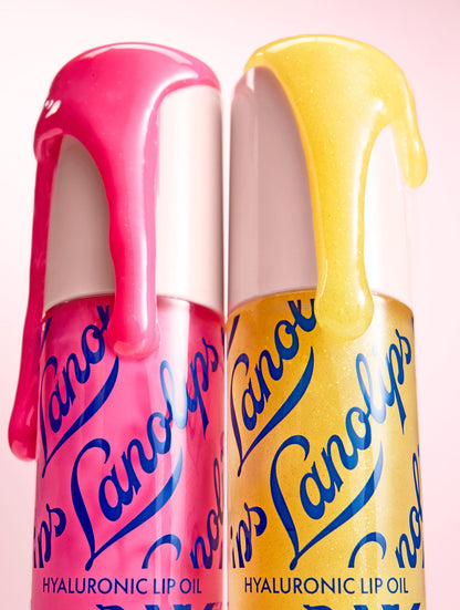 Product shot of the Lanolips Hyaluronic Lip Oil in Raspberry and Honey, featuring the closed bottle with lip oil dripping from the sides. The lip oil contains lanolin, hyaluronic acid, and vitamin E for deep hydration, nourishment, and a glossy finish.